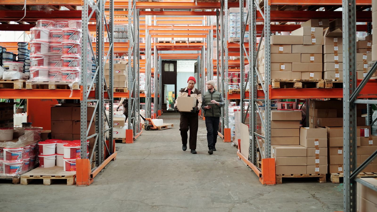 Warehouse staff working beside shelves of packages.