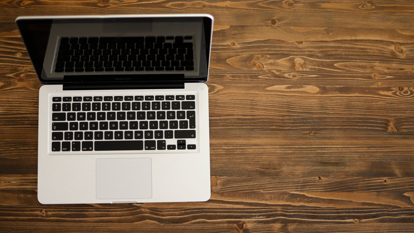 A laptop on a rustic wooden desk viewed from above.