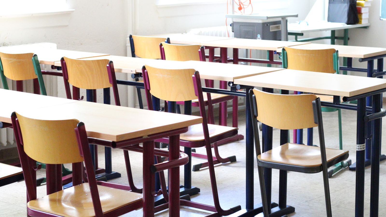 A bright classroom with wooden desks and chairs.
