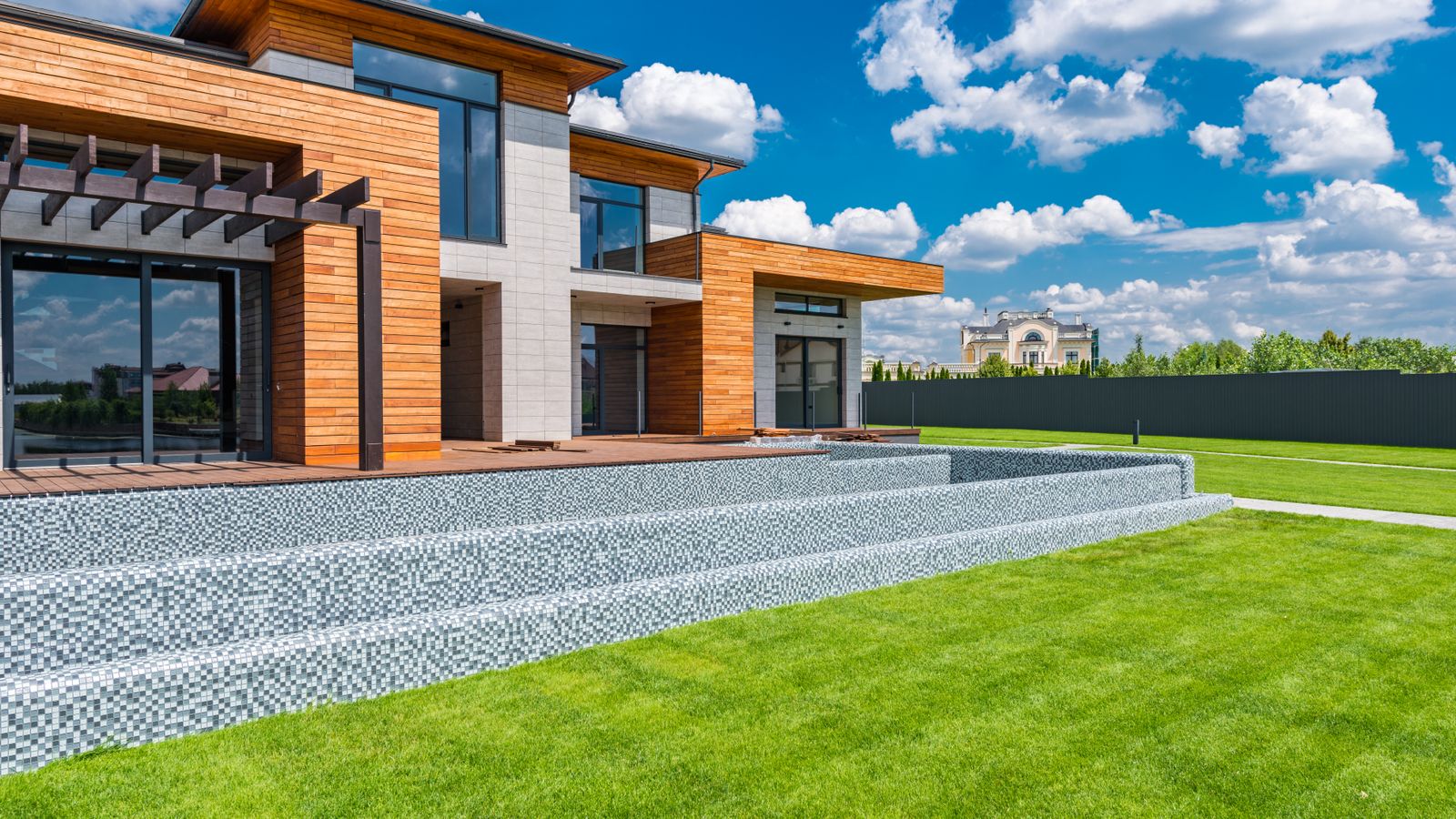A modern house overlooking a green lawn.