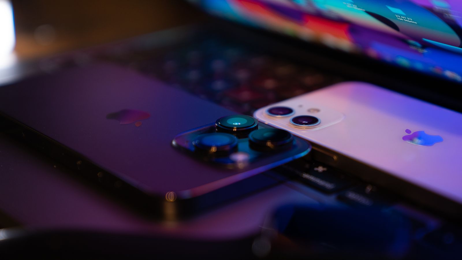 Two smartphones resting on a laptop keyboard.