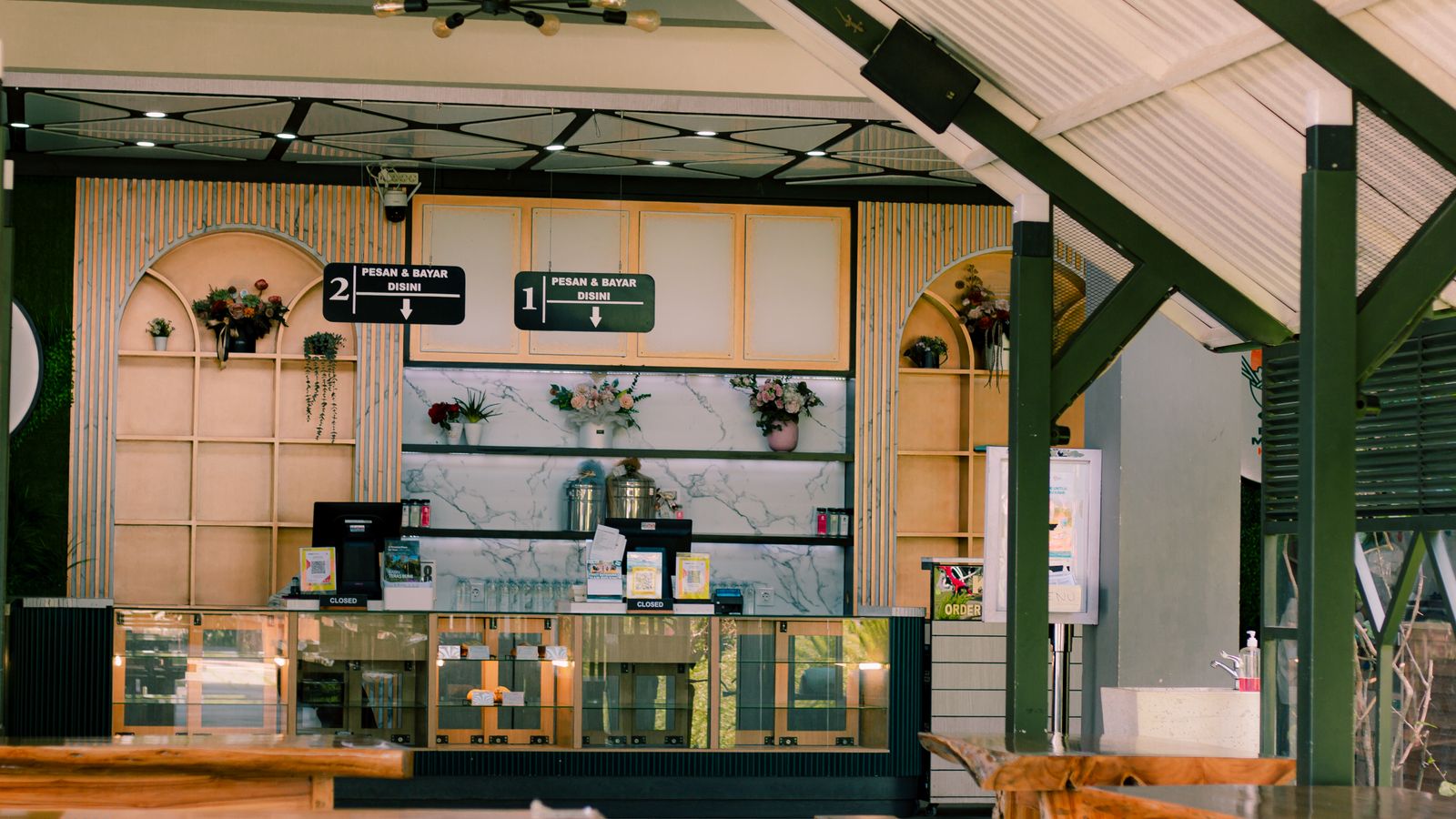 A café counter with wooden details and potted plants.