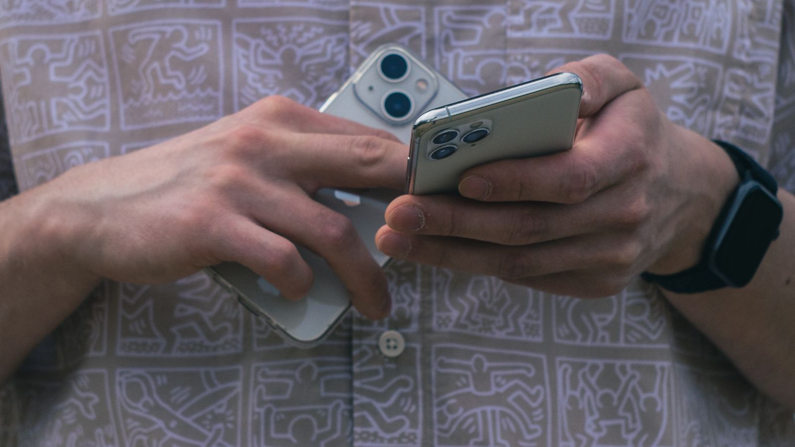 Hands holding two mobile phones.