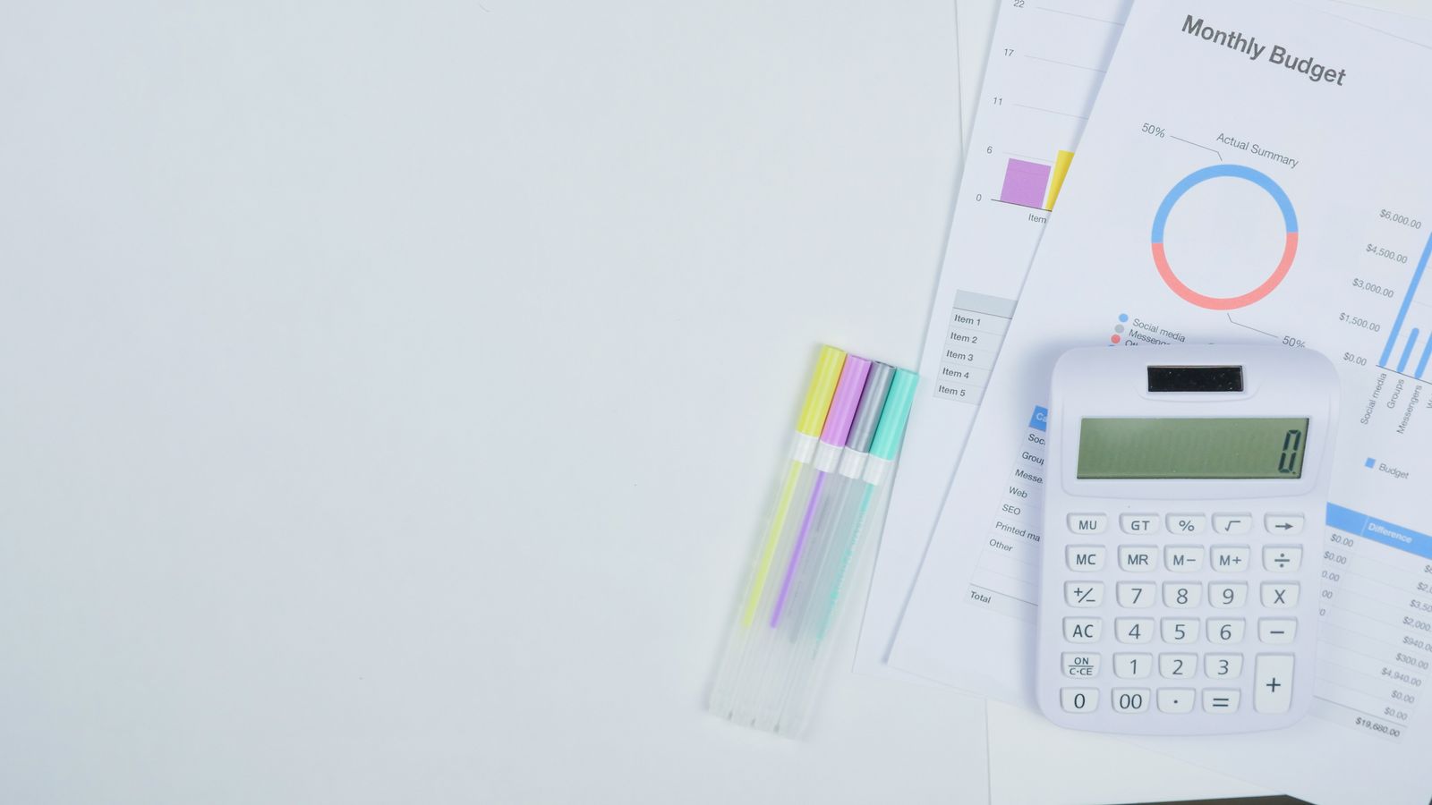 Budget planning documents, a calculator, and pens on a desk.