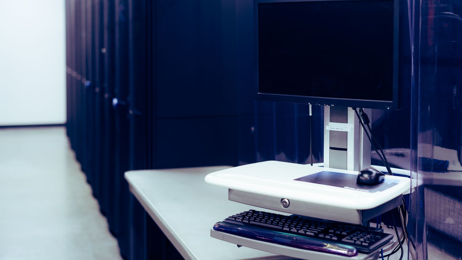 A computer monitor beside server hardware.